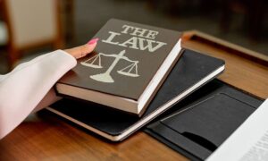 Closeup image of a law book titled 'The Law' on a wooden desk with scales of justice. - Photo by Mikhail Nilov on Pexels