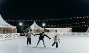A family enjoying ice skating together on an outdoor rink at night under festive string lights. - Photo by cottonbro studio on Pexels