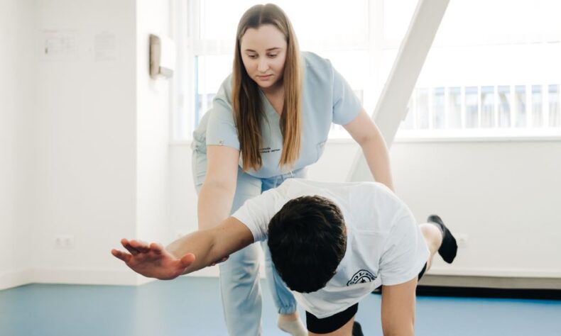 A physiotherapist assists a patient in stretching exercises indoors. - Photo by Funkcinės Terapijos Centras on Pexels