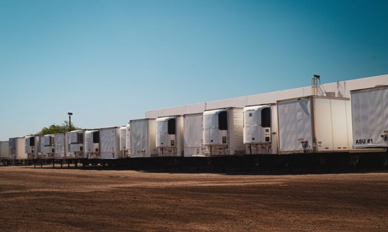Refrigerated trucks parked in an industrial lot under a clear blue sky on a sunny day. - Photo by Tom Jackson on Pexels
