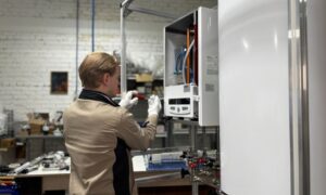 Technician inspects and repairs a heating system in an industrial workshop setting. - Photo by МОБО Модульные Котельные on Pexels