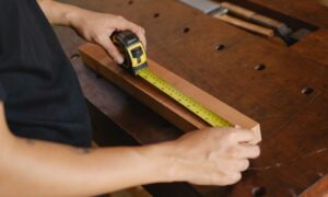 Precise unrecognizable male carpenter accurately measuring wooden detail while using ruler during work at workbench with instruments in professional studio - Photo by Ono Kosuki on Pexels